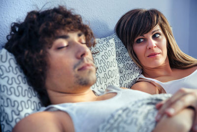 Thoughtful woman with boyfriend lying down on bed