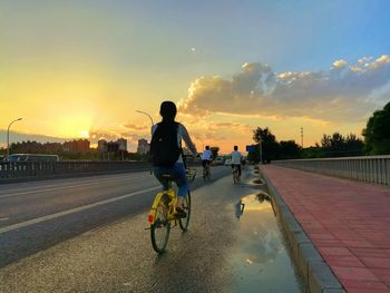 Rear view of man riding bicycle on road in city