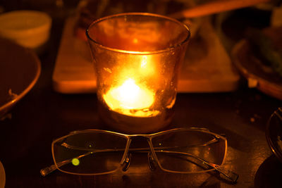 Close-up of eyeglasses by candle on table