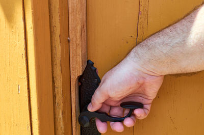 Close-up of man holding hands against wall