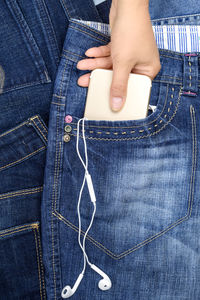 Cropped hand removing mobile phone from pocket of jeans