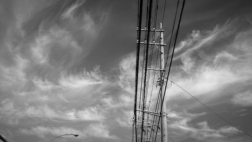 Low angle view of power lines against cloudy sky