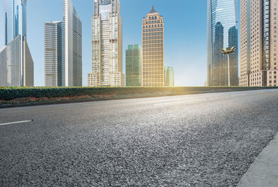 City street by modern buildings against sky