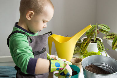 Side view of cute boy holding table at home