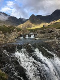 Scenic view of river flowing amidst mountains against sky