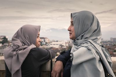 Close-up of young couple in city against sky