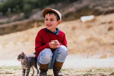 Cute smiling boy looking away with cat outdoors