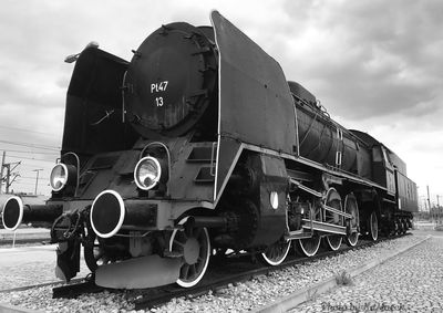 Train on railroad track against cloudy sky