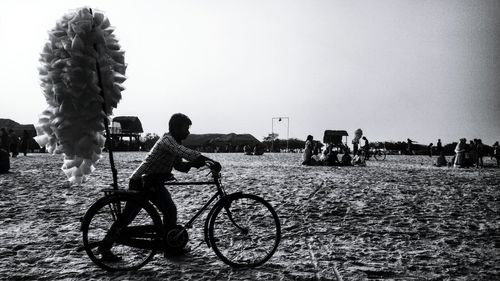 People riding bicycles on street against clear sky