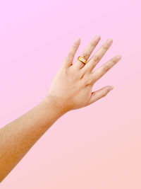 Close-up of woman hand over pink background