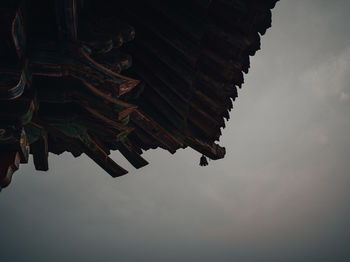 Low angle view of cross on roof against sky
