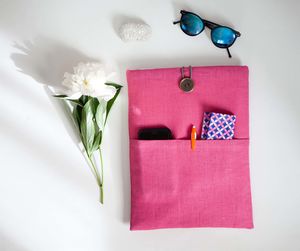 Directly above shot of flowers with bag and sunglasses on white table