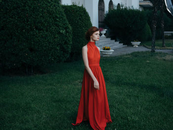 Woman standing by plants against trees