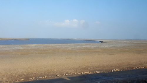 View of calm beach against blue sky