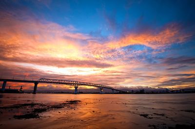 Bridge over sea against sky during sunset
