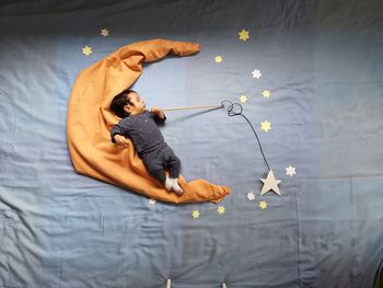 High angle view of baby boy with star decorations sleeping on bed at home