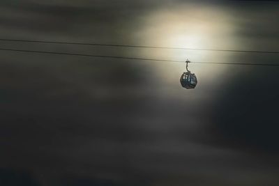 Low angle view of illuminated lighting equipment hanging on cable