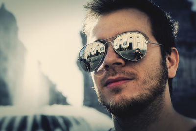 Close-up portrait of young adult stylish model wearing sunglasses in the center of city