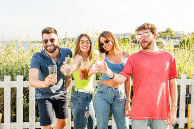 Smiling friends holding drinks standing outdoors