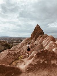 Rear view of man walking on mountain against sky