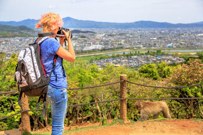 Woman photographing against sky