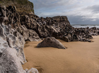 Rock formation on beach against sky
