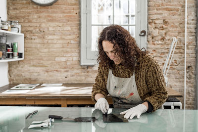 Woman artist preparing ink for an art print. using an ink stick