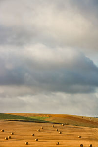 Hay bales on field against sky