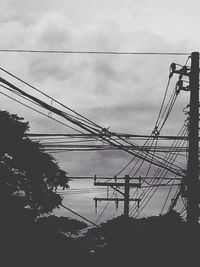 Low angle view of electricity pylon against cloudy sky