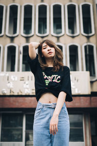 Full length of young woman standing against building