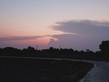 Silhouette trees on field against sky at sunset