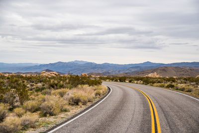 Curved road in joshua tree national park leading to hill scape far off