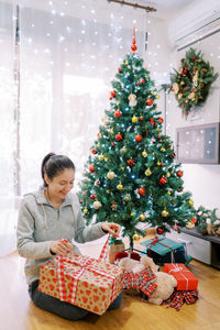 Portrait of smiling girl decorating christmas tree at home