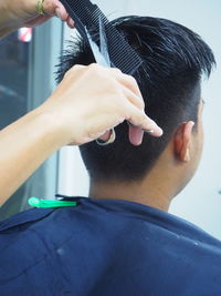 Cropped hands of barber cutting customer hair in salon