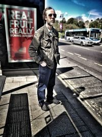 Portrait of young man standing on footpath