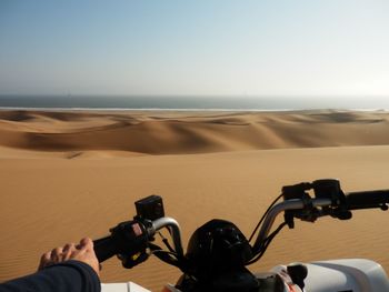 Man riding motorcycle on beach against clear sky