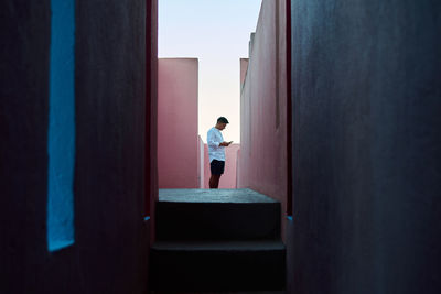 Young man absorbed in his mobile phone between colorful walls