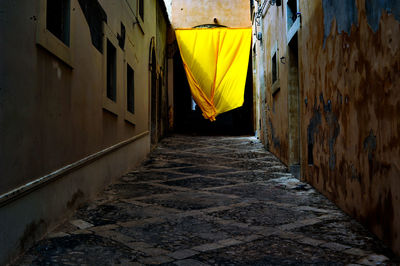 Yellow canvas in alley amidst residential buildings