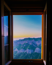 Scenic view of mountains against sky seen through window