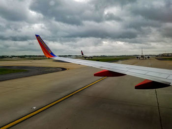 Airplane flying over airport runway against sky