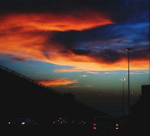 Silhouette of street light against cloudy sky