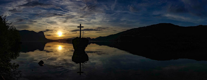 Silhouette man by lake against sky during sunset