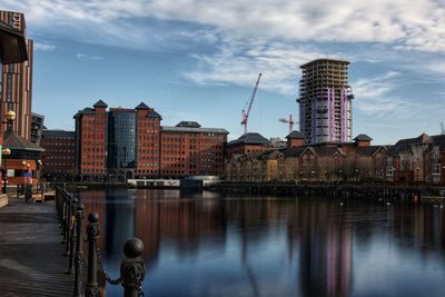 Buildings by river against sky in city