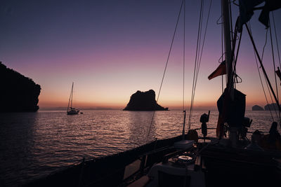 Silhouette sailboats in sea against sky during sunset