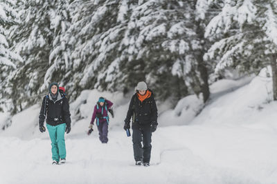 Group of three people walking in the snow toward camera manning park