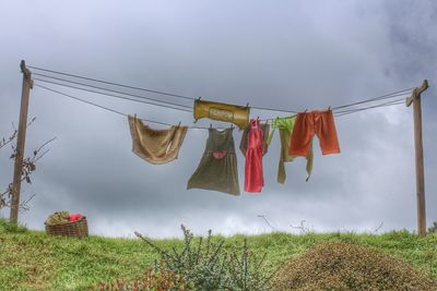 Clothes drying on clothesline over field against sky