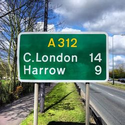 Low angle view of road sign against cloudy sky