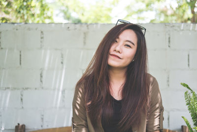 Portrait of young woman with long hair against wall