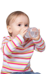 Portrait of cute boy drinking glass against white background