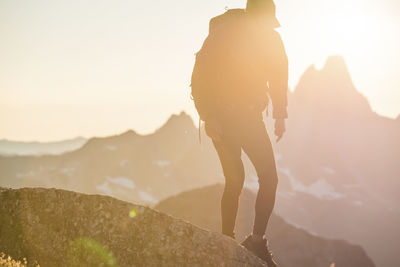 Silhouetted view of backpacker on the move on mountain summit.